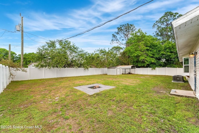 view of yard featuring a fenced backyard, an outdoor structure, a fire pit, and a shed