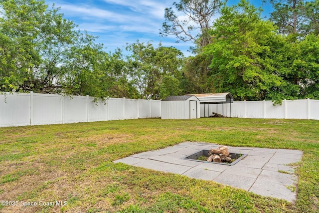 view of yard with an outdoor fire pit, a patio, a fenced backyard, a storage unit, and an outdoor structure