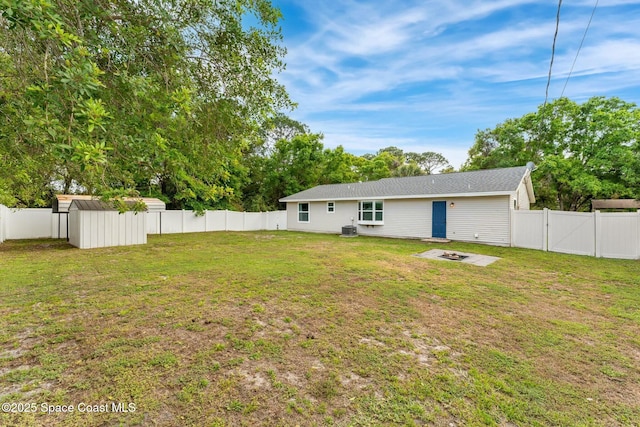 back of house with an outbuilding, a lawn, an outdoor fire pit, a gate, and a fenced backyard