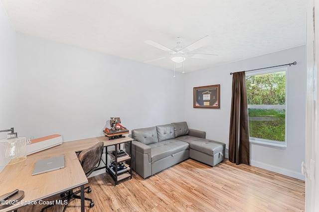 office space featuring baseboards, ceiling fan, and light wood finished floors