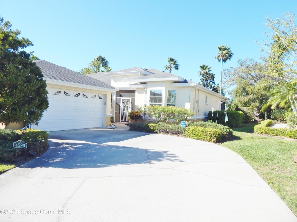 view of front facade featuring concrete driveway, a front lawn, a garage, and stucco siding