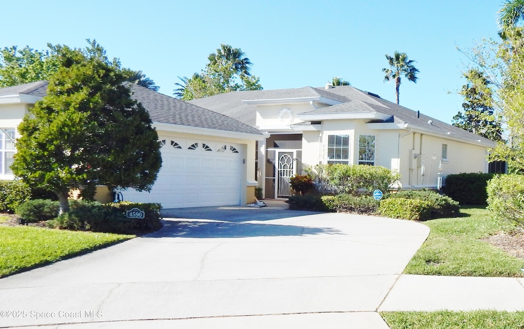 view of front facade featuring a shingled roof, concrete driveway, a garage, and stucco siding