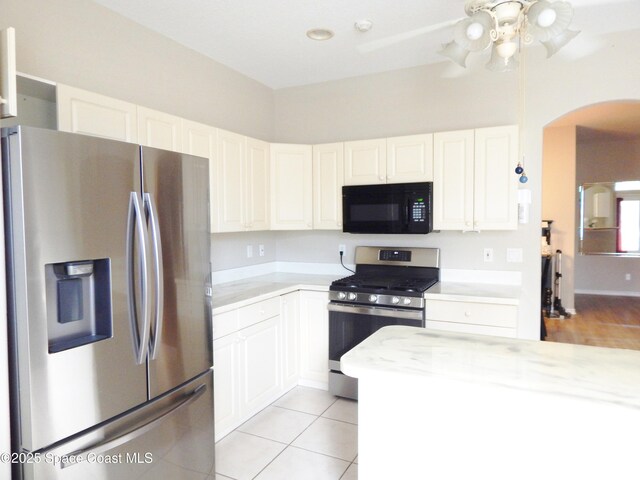 4590 Brantford Ct, Rockledge, FL 32955 - kitchen featuring appliances with stainless steel finishes, light countertops, arched walkways, a ceiling fan, and white cabinetry