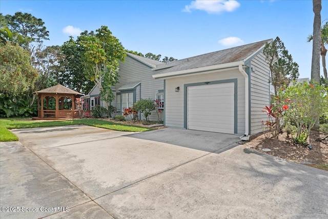 ranch-style house featuring a garage, concrete driveway, and a gazebo