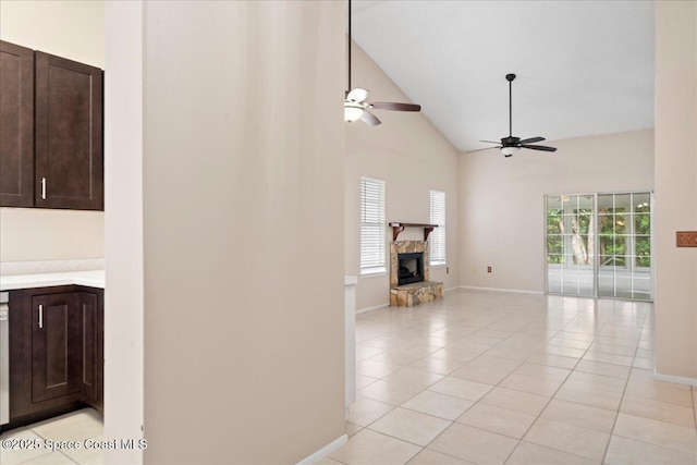 interior space featuring a fireplace, light tile patterned floors, ceiling fan, high vaulted ceiling, and baseboards