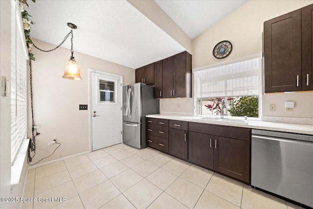 kitchen featuring light countertops, appliances with stainless steel finishes, light tile patterned flooring, a sink, and dark brown cabinetry