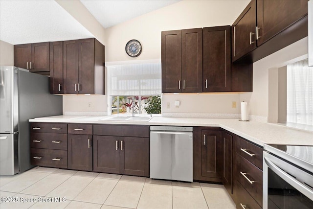 kitchen featuring stainless steel appliances, lofted ceiling, a sink, and dark brown cabinets