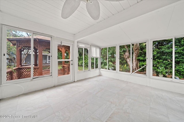 unfurnished sunroom with beamed ceiling and a ceiling fan