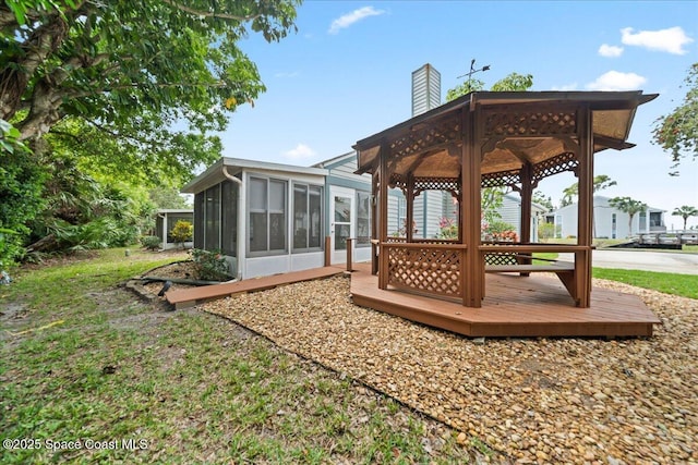 exterior space with a sunroom, a chimney, a deck, and a gazebo