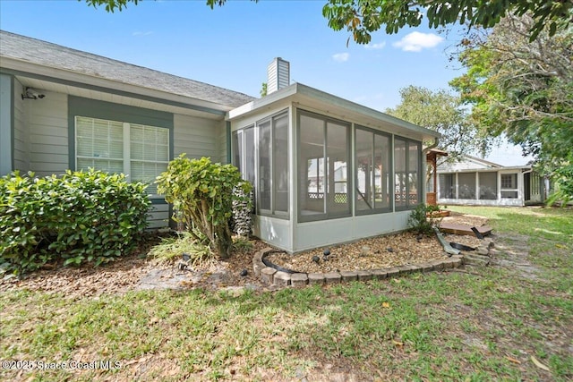 rear view of house featuring a sunroom and a chimney