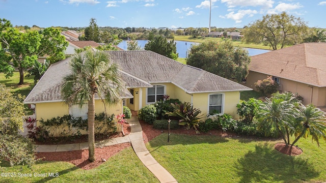 view of front of property with a shingled roof, a water view, a front lawn, and stucco siding