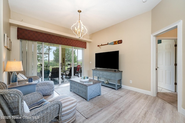 living room with an inviting chandelier, baseboards, and light wood-style floors