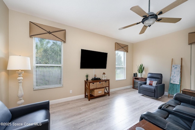 living room featuring a ceiling fan, light wood-style flooring, and baseboards