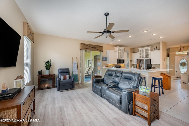 living room with recessed lighting, a glass covered fireplace, a ceiling fan, and a healthy amount of sunlight