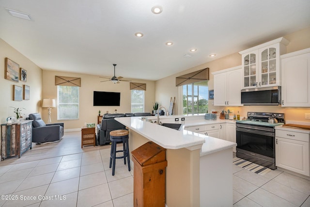 kitchen featuring a breakfast bar, light tile patterned floors, appliances with stainless steel finishes, open floor plan, and a sink