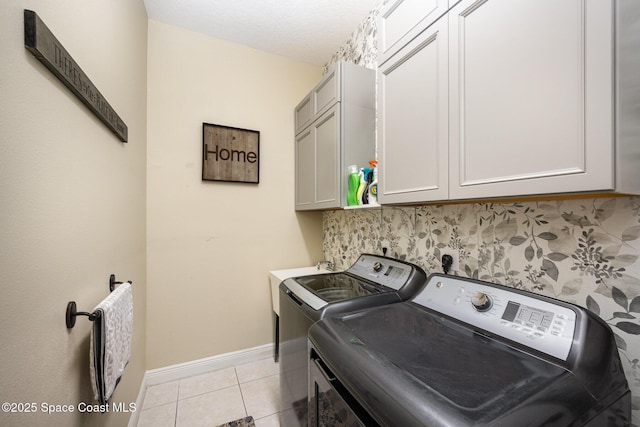 clothes washing area with cabinet space, light tile patterned floors, baseboards, and separate washer and dryer