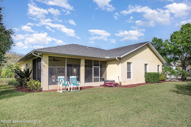 rear view of house featuring a sunroom, roof with shingles, a lawn, and stucco siding