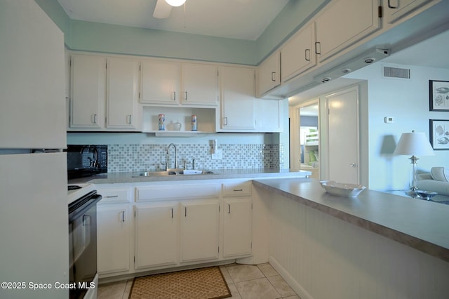 kitchen featuring visible vents, freestanding refrigerator, range with electric cooktop, a sink, and black microwave