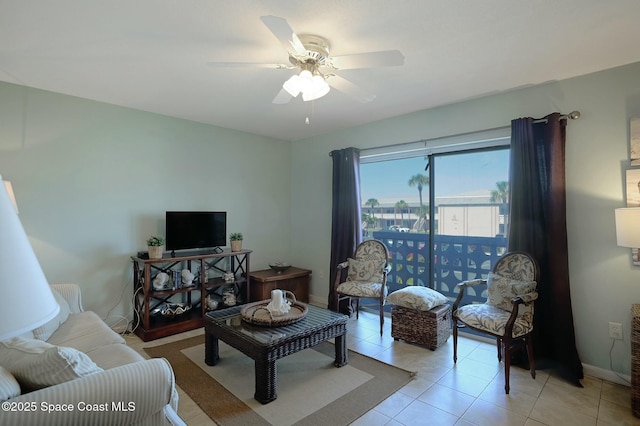 living room with light tile patterned floors, baseboards, and ceiling fan