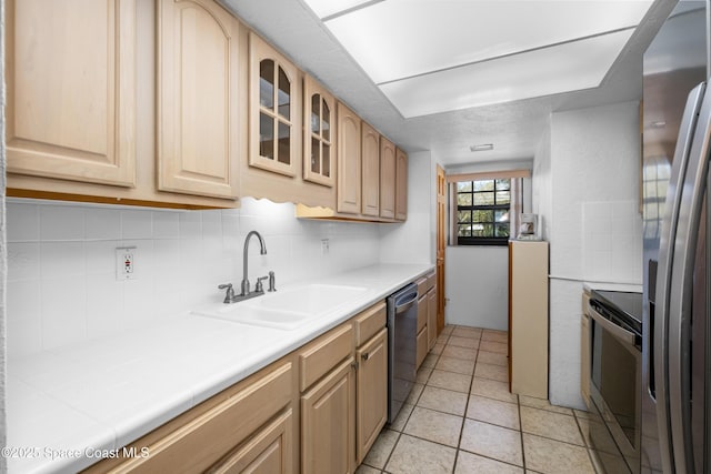 kitchen featuring a sink, stainless steel appliances, decorative backsplash, and light brown cabinets