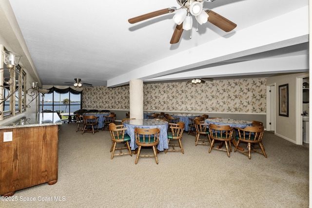 dining area with beamed ceiling, wallpapered walls, carpet, and a ceiling fan