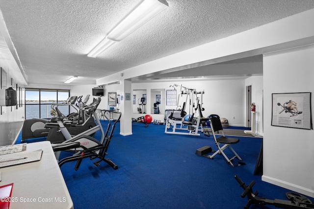 gym with a textured ceiling and baseboards