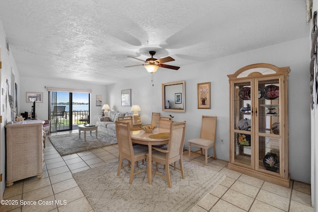 dining room featuring a textured ceiling, light tile patterned flooring, and a ceiling fan