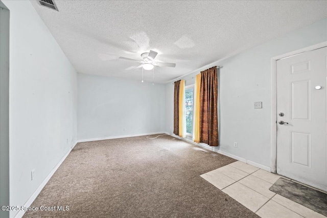 empty room featuring baseboards, visible vents, a ceiling fan, light colored carpet, and a textured ceiling