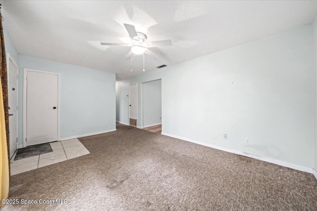 carpeted spare room with a ceiling fan, baseboards, visible vents, and a textured ceiling