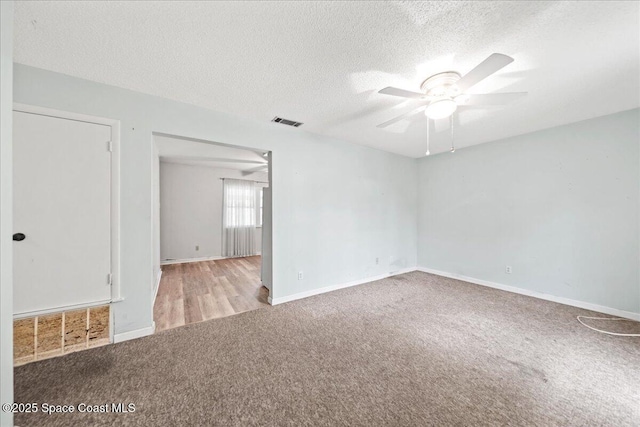 empty room with a textured ceiling, carpet floors, ceiling fan, and visible vents