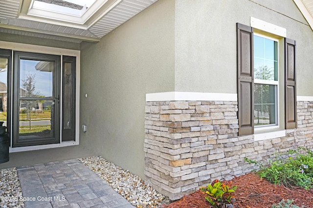 doorway to property featuring stone siding and stucco siding