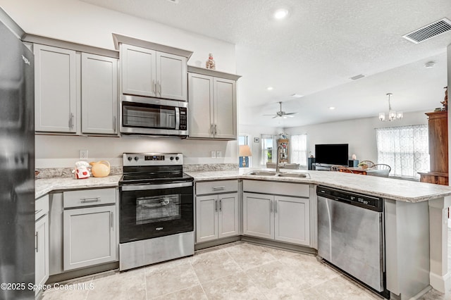 kitchen featuring visible vents, appliances with stainless steel finishes, a peninsula, gray cabinets, and a sink