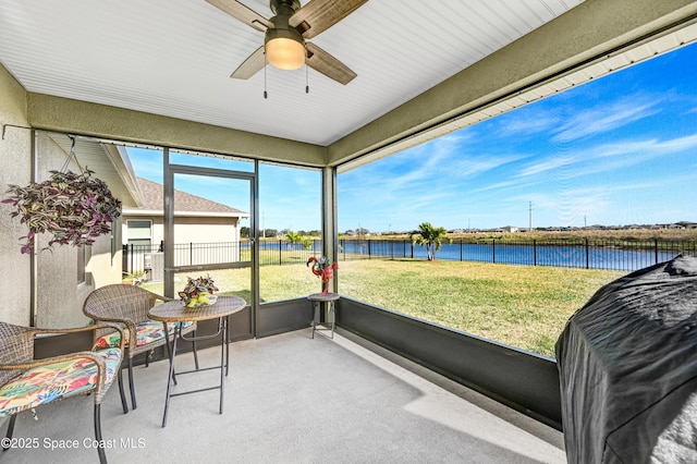 sunroom / solarium featuring a water view and a ceiling fan