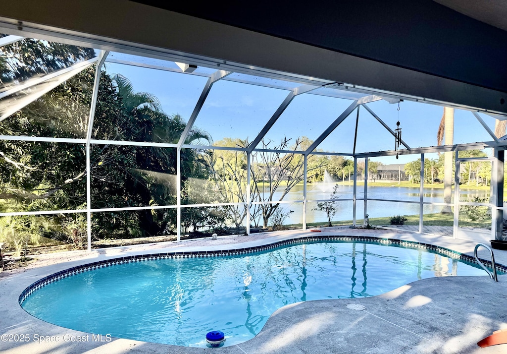 pool with a patio, a water view, and glass enclosure