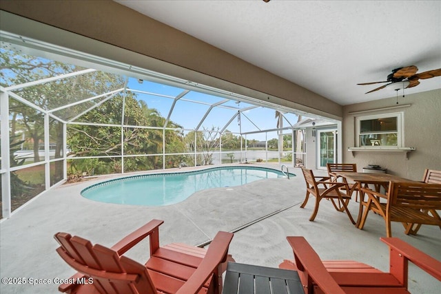 outdoor pool featuring glass enclosure, ceiling fan, outdoor dining space, and a patio area