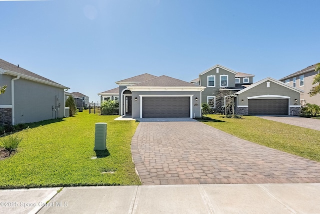 view of front of home with decorative driveway, an attached garage, a front lawn, and stucco siding