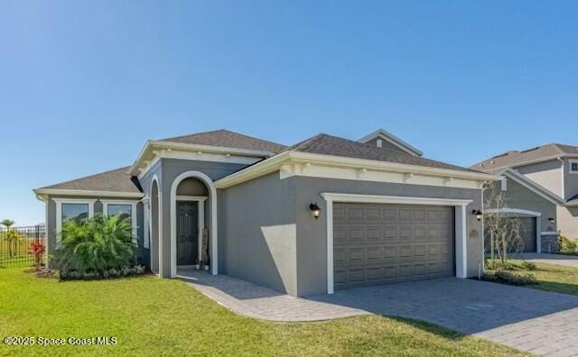 view of front of home featuring stucco siding, an attached garage, fence, decorative driveway, and a front yard