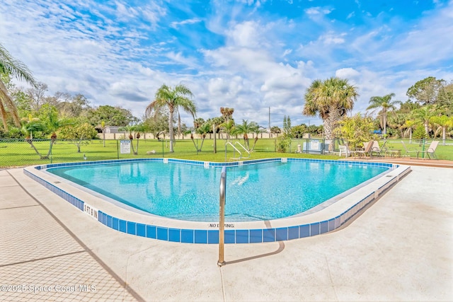 pool featuring a yard, a patio, and fence