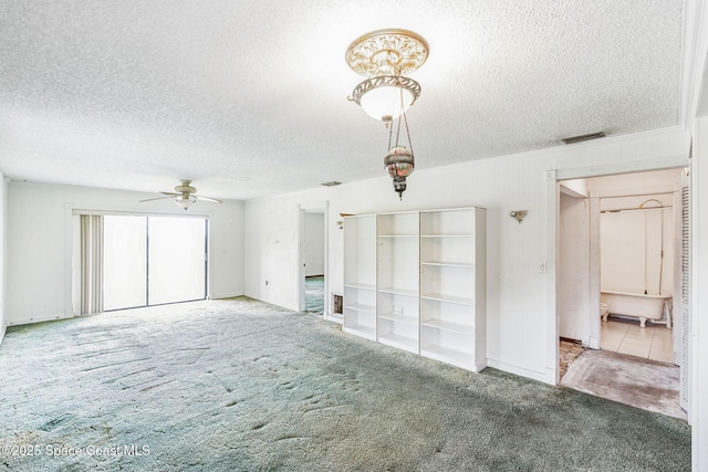 interior space with a textured ceiling, carpet floors, visible vents, and a ceiling fan