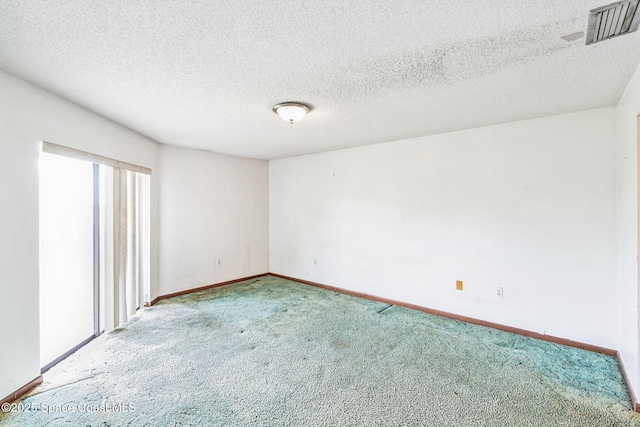 carpeted empty room featuring baseboards, visible vents, and a textured ceiling