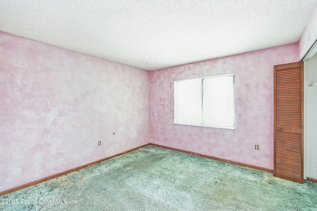 carpeted empty room with a textured ceiling and baseboards