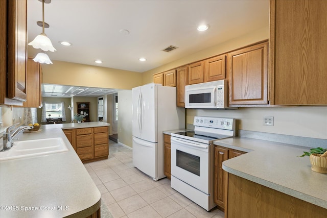 kitchen featuring white appliances, visible vents, a peninsula, light countertops, and a sink