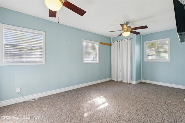 carpeted empty room featuring a ceiling fan and baseboards