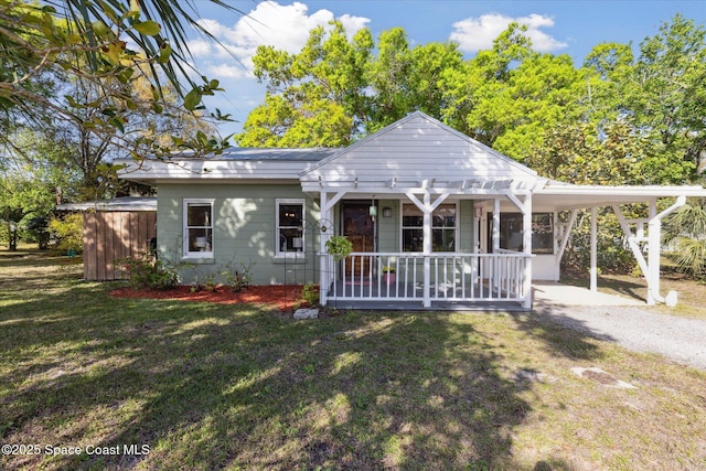 view of front of house featuring covered porch, a carport, a front lawn, and driveway