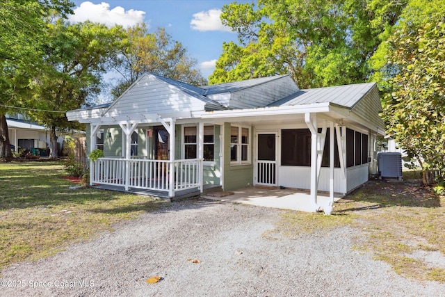 bungalow-style home featuring a front yard, a sunroom, central AC, and metal roof