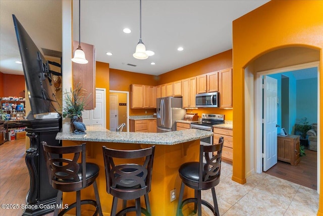 kitchen featuring visible vents, a peninsula, light stone countertops, stainless steel appliances, and recessed lighting