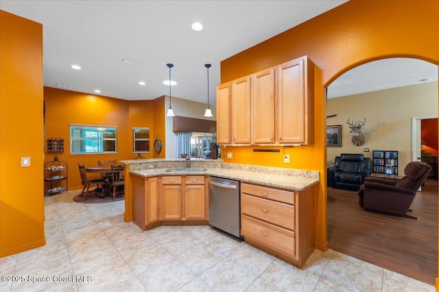 kitchen featuring arched walkways, a peninsula, light stone countertops, stainless steel dishwasher, and a sink