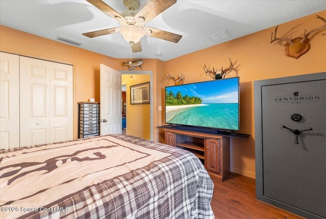 bedroom with a ceiling fan, visible vents, a closet, and wood finished floors