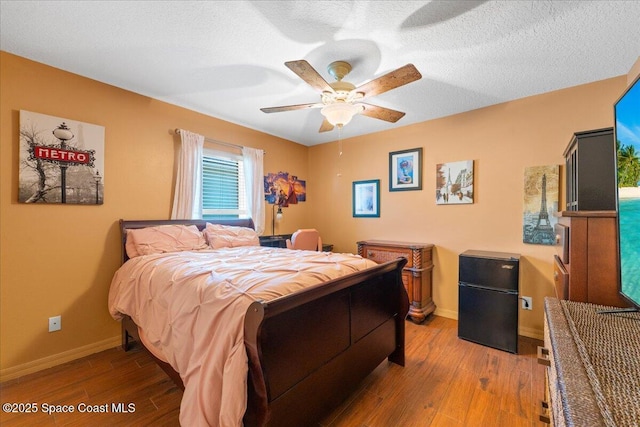 bedroom featuring a textured ceiling, baseboards, and wood finished floors