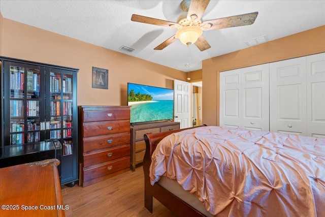 bedroom featuring light wood finished floors, a closet, visible vents, and a ceiling fan